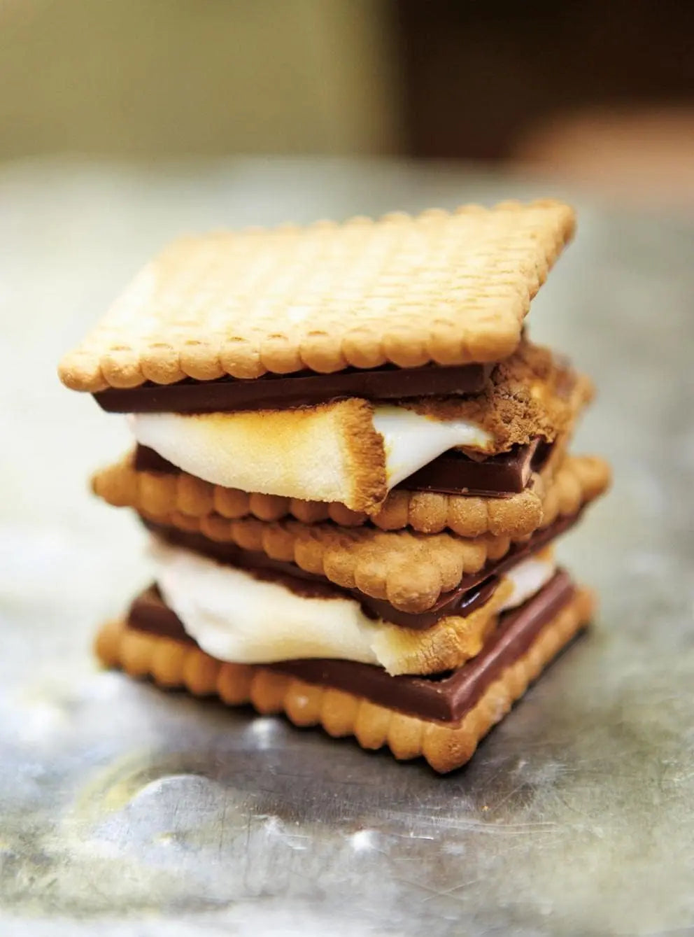 Finished s’more showing toasted marshmallow and melted chocolate between crisp biscuits